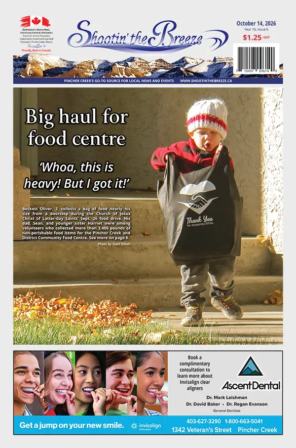 Three-year-old Beckett Oliver carries a large black bag of donated food along a sidewalk.
